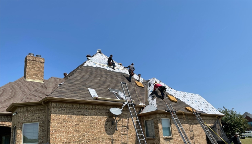 Roofing contractors repairing a roof damaged from hail.