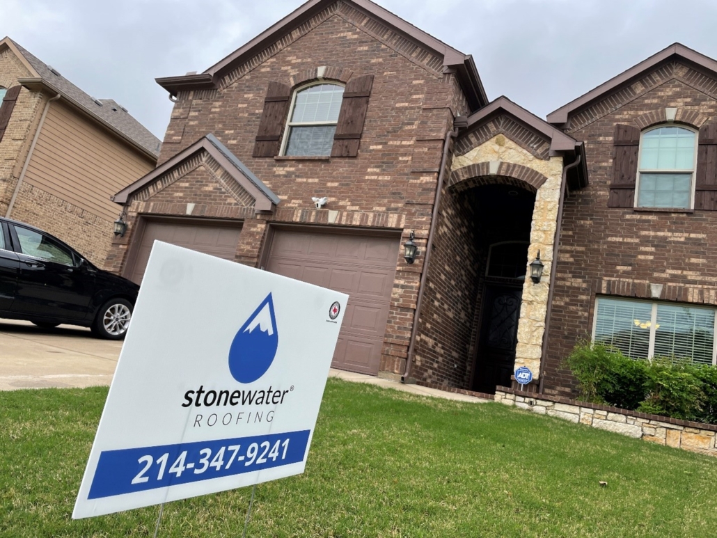 A Stonewater Roofing sign in front of a home with a roof replacement