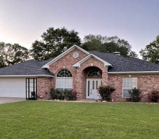 A brick house where you can see various parts of the roof, including high-contrast white soffit and fascia