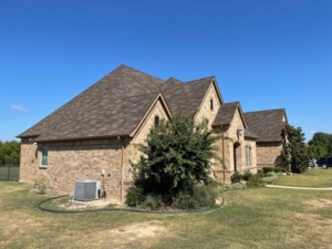 The side of a brick house with a sloped roof and several gutter downspouts
