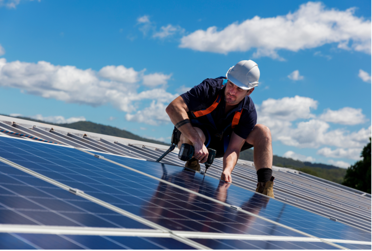 A professional roofer installs solar panels on a commercial building.
