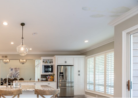 Kitchen inside of a home with interior water leaks shown on the ceiling.