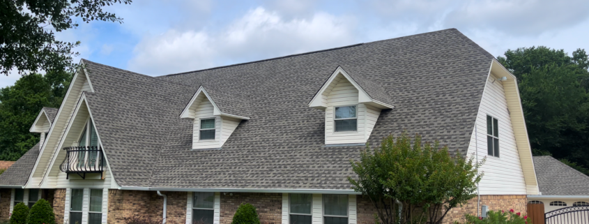 A large brick-fronted home with a prominent shingled roof.