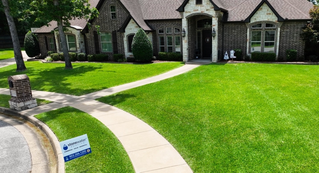 A newly roofed house with a Stonewater Roofing contractor’s sign in front.