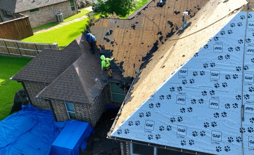 A team of roofing contractors working on replacing the roof of a house.