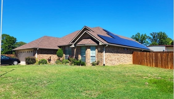 A home with solar panels on its roof. The sun is low in the sky and reflecting off the home’s windows.