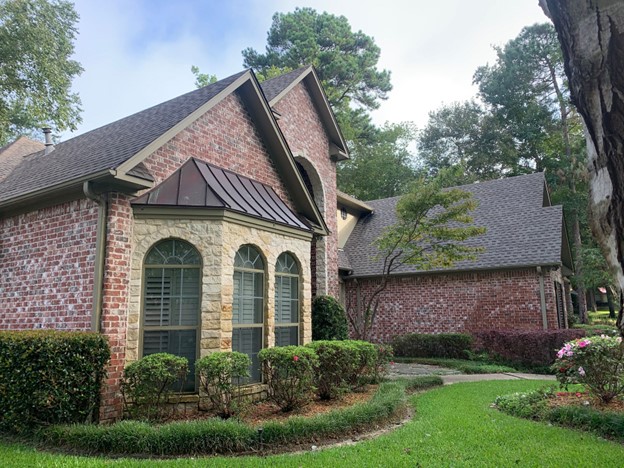 A brick home with asphalt architectural shingles. For some homes, these are the best type of roof shingles to fit unusual architectural flourishes and certain types of slope roofing.