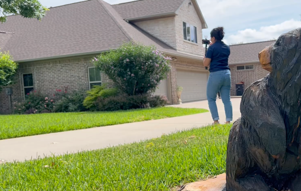 A woman snaps a picture of her home after noticing she has a leaky roof. This will make it easier for her to make an insurance claim.
