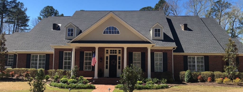 A large home with a columned porch and a brand-new shingle roof.